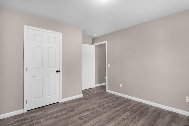 unfurnished bedroom featuring a closet and dark wood-type flooring