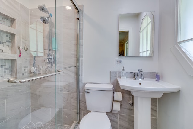 bathroom featuring tile walls, toilet, and a shower with shower door