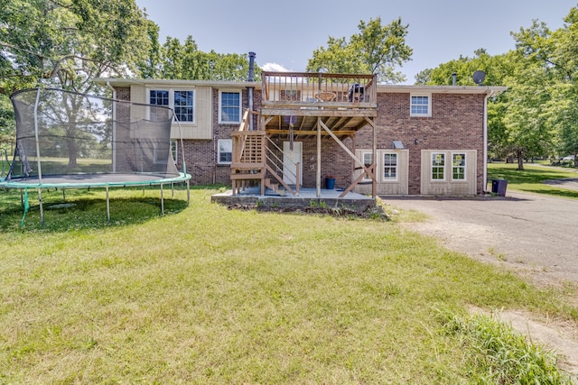 back of property featuring a yard, a trampoline, and a wooden deck