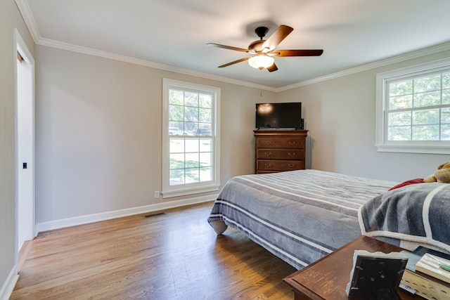 bedroom featuring ornamental molding, ceiling fan, hardwood / wood-style floors, and multiple windows