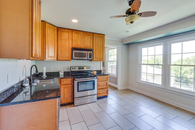 kitchen featuring ceiling fan, appliances with stainless steel finishes, sink, dark stone counters, and crown molding