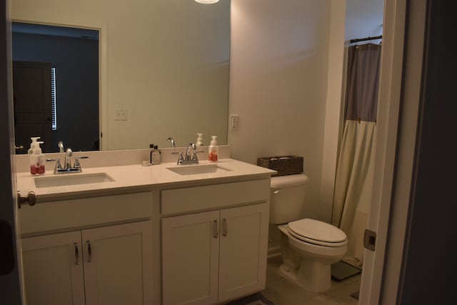 bathroom with tile flooring, double sink vanity, and toilet