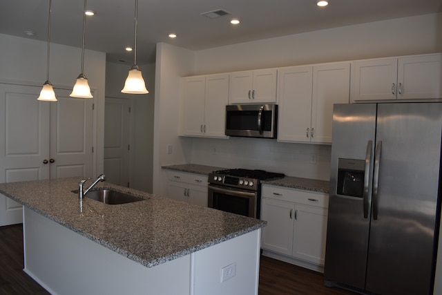 kitchen with appliances with stainless steel finishes, hanging light fixtures, sink, white cabinetry, and dark hardwood / wood-style floors