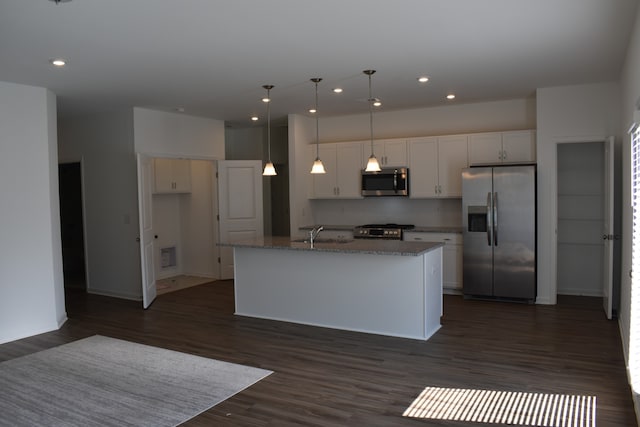 kitchen featuring appliances with stainless steel finishes, white cabinets, dark hardwood / wood-style floors, an island with sink, and backsplash