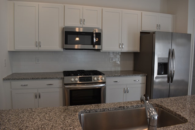 kitchen featuring appliances with stainless steel finishes, backsplash, white cabinetry, and stone counters