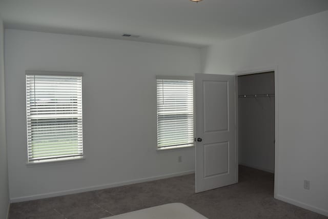 unfurnished bedroom featuring a closet and dark carpet