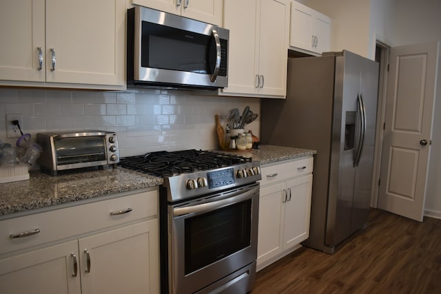 kitchen with light stone counters, dark hardwood / wood-style flooring, white cabinets, stainless steel appliances, and tasteful backsplash