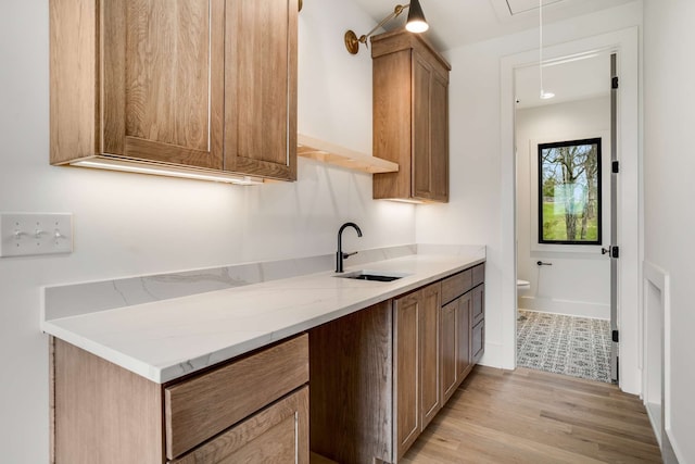 kitchen featuring light stone countertops, sink, and light hardwood / wood-style flooring