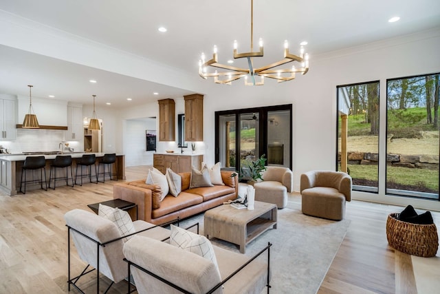 living room featuring light hardwood / wood-style floors, a notable chandelier, and crown molding