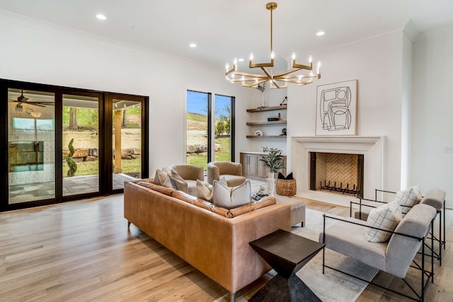 living room with light wood-type flooring, ornamental molding, and ceiling fan with notable chandelier