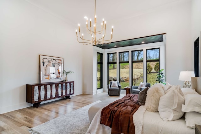 bedroom featuring a chandelier, a high ceiling, and light hardwood / wood-style flooring