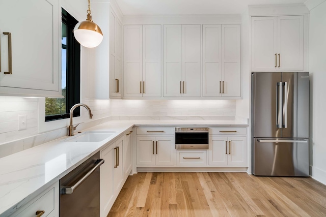 kitchen featuring hanging light fixtures, appliances with stainless steel finishes, light hardwood / wood-style floors, sink, and white cabinets