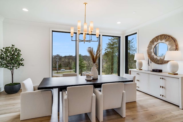 dining area featuring ornamental molding, light hardwood / wood-style floors, and an inviting chandelier