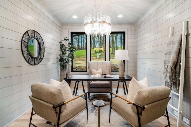 living area with an inviting chandelier, wooden walls, and light hardwood / wood-style floors