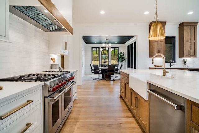 kitchen featuring decorative light fixtures, white cabinetry, light wood-type flooring, and stainless steel appliances