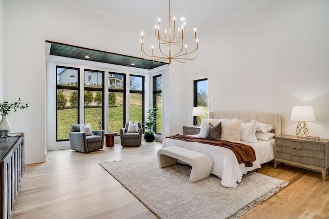 bedroom with a towering ceiling, a notable chandelier, and light wood-type flooring