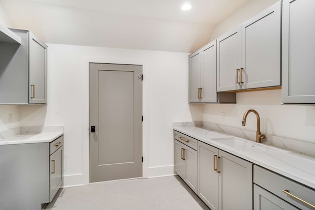 kitchen featuring light tile floors, light stone countertops, and gray cabinetry