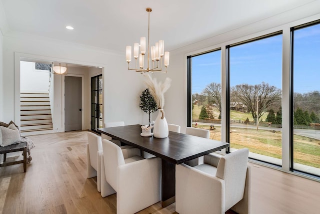 dining area with light hardwood / wood-style floors, ornamental molding, a notable chandelier, and a wealth of natural light