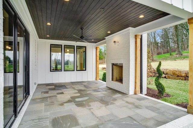 view of patio with an outdoor brick fireplace and ceiling fan