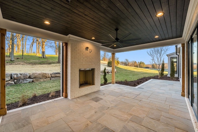 view of patio with an outdoor brick fireplace and ceiling fan