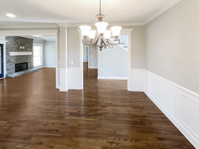 interior space with ornamental molding, a notable chandelier, dark wood-type flooring, and a fireplace