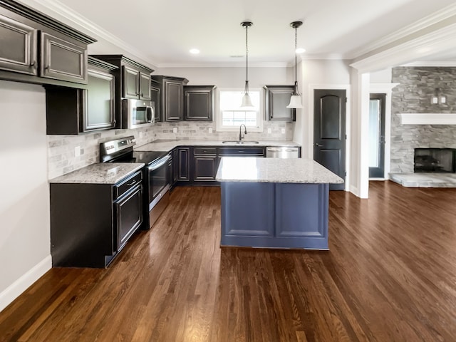 kitchen with stainless steel appliances, decorative light fixtures, a fireplace, backsplash, and dark hardwood / wood-style flooring