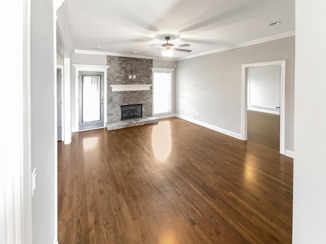 unfurnished living room featuring a stone fireplace, dark hardwood / wood-style floors, ceiling fan, and crown molding