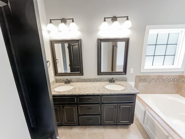 bathroom featuring double sink, large vanity, tile floors, and a bath to relax in