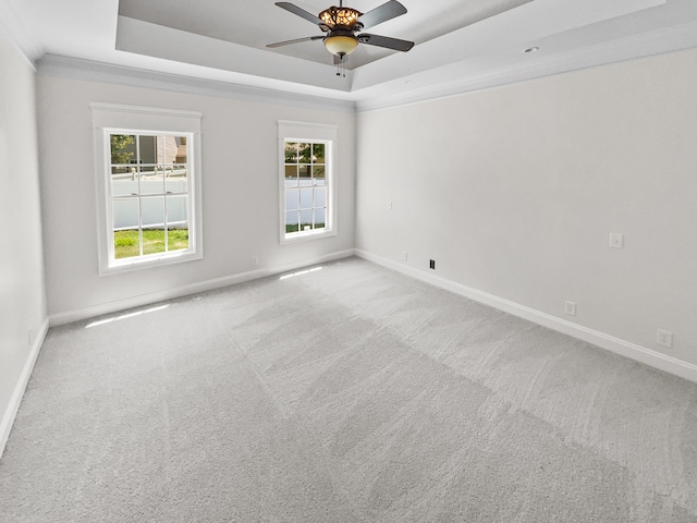 empty room featuring light colored carpet, ceiling fan, and a tray ceiling