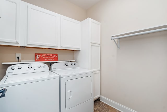 laundry area with dark tile flooring, cabinets, and washing machine and dryer