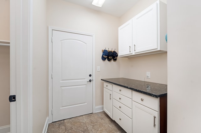 kitchen featuring light tile flooring, white cabinetry, and dark stone countertops