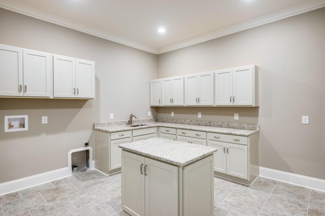 kitchen with white cabinetry, light tile flooring, sink, light stone counters, and crown molding