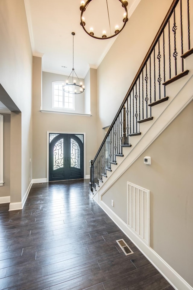 foyer with dark hardwood / wood-style flooring, french doors, a chandelier, and a towering ceiling