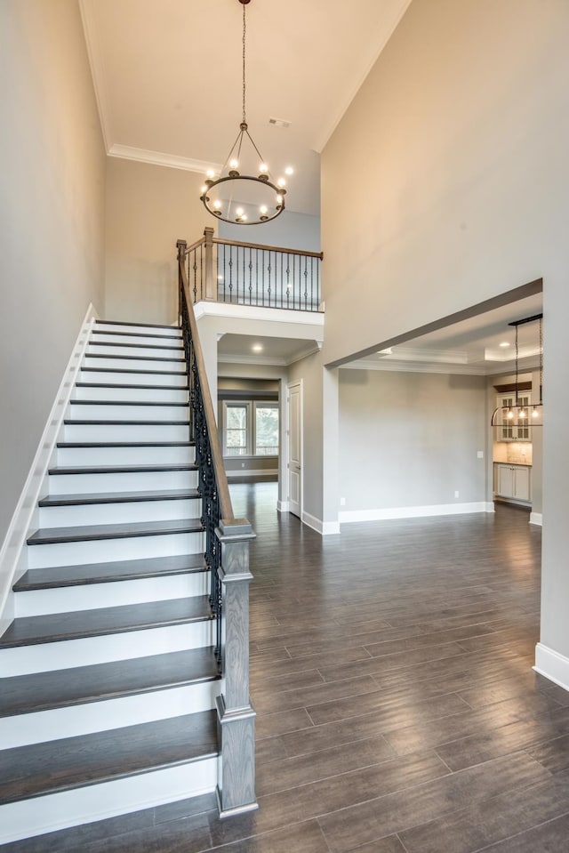 foyer entrance featuring crown molding, a notable chandelier, a high ceiling, and dark hardwood / wood-style floors