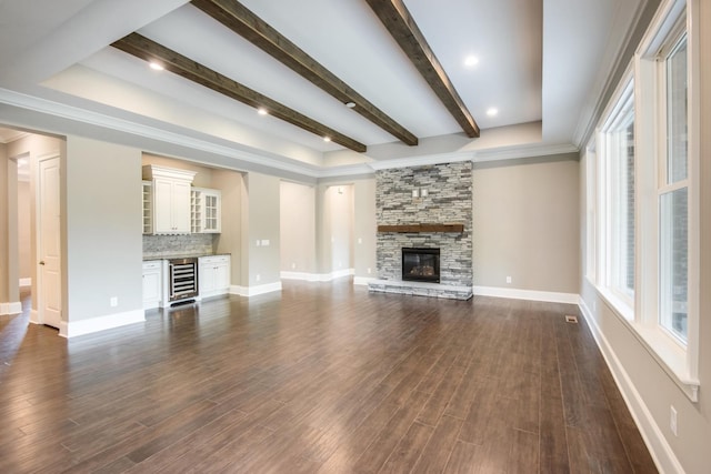 unfurnished living room with beam ceiling, dark hardwood / wood-style flooring, a stone fireplace, and wine cooler