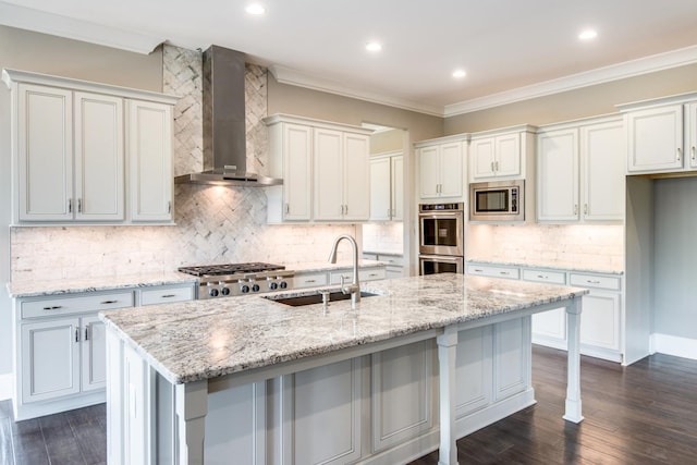 kitchen with appliances with stainless steel finishes, white cabinetry, wall chimney exhaust hood, and tasteful backsplash