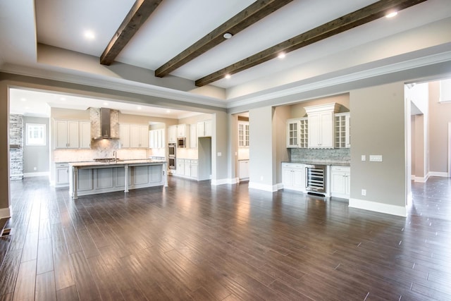 unfurnished living room featuring beam ceiling, wine cooler, sink, and dark hardwood / wood-style flooring