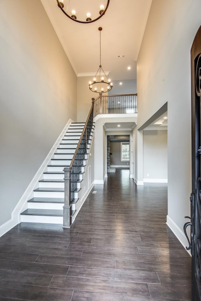 entrance foyer featuring an inviting chandelier, dark wood-type flooring, ornamental molding, and a high ceiling