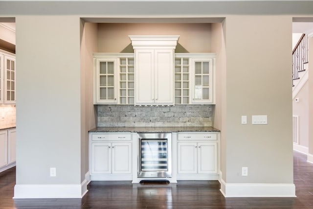 bar featuring tasteful backsplash, stone counters, beverage cooler, dark hardwood / wood-style floors, and white cabinets