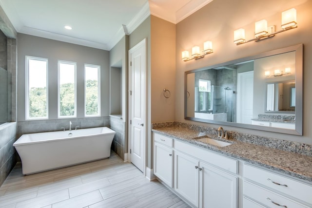 bathroom with tile flooring, tile walls, vanity, ornamental molding, and a bath