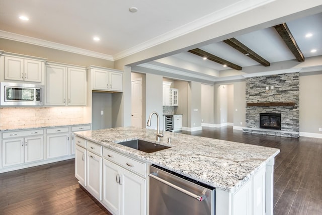 kitchen with an island with sink, beamed ceiling, appliances with stainless steel finishes, sink, and dark hardwood / wood-style flooring