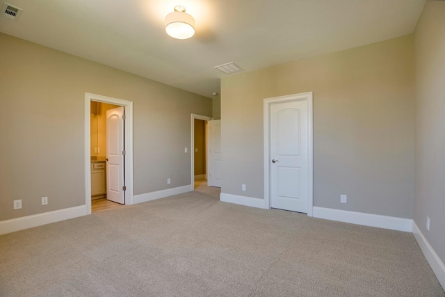 unfurnished bedroom featuring ensuite bath and light colored carpet