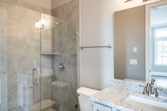 bathroom featuring toilet, large vanity, and a shower with shower door