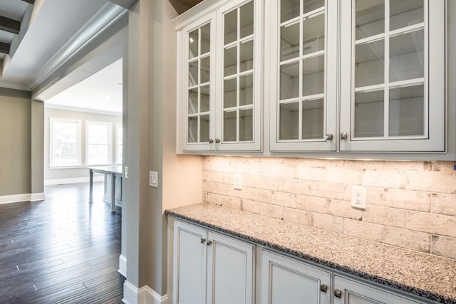 interior space with dark hardwood / wood-style flooring, light stone counters, white cabinets, backsplash, and ornamental molding