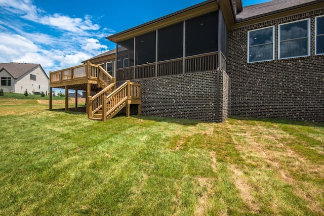 rear view of property featuring a sunroom, a wooden deck, and a yard