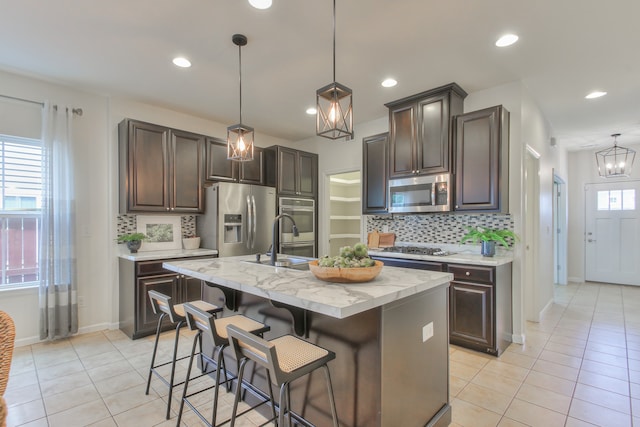 kitchen featuring appliances with stainless steel finishes, backsplash, sink, and an island with sink