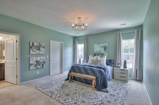 bedroom featuring connected bathroom, light carpet, and a chandelier