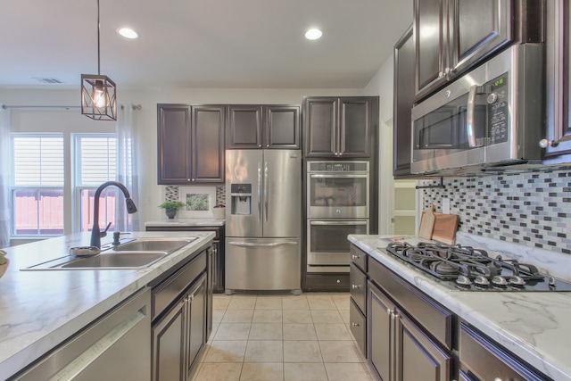 kitchen with decorative light fixtures, light tile floors, stainless steel appliances, backsplash, and sink