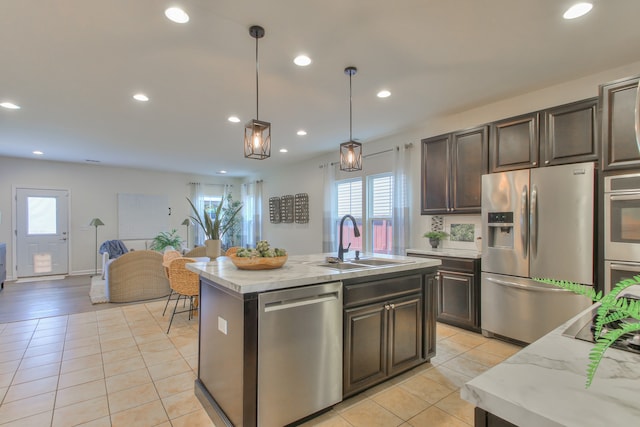 kitchen with decorative light fixtures, a kitchen island with sink, sink, stainless steel appliances, and dark brown cabinetry