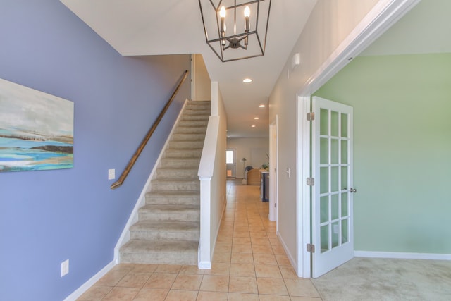 staircase featuring light tile floors and an inviting chandelier